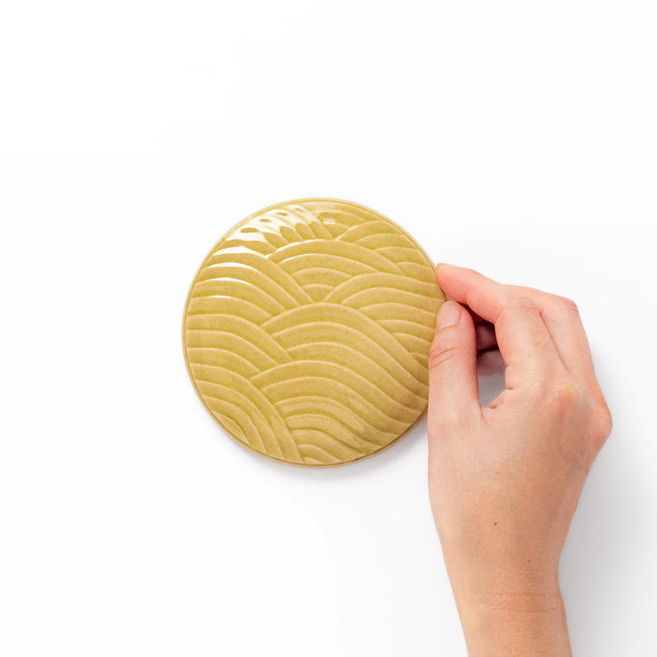 Yellow porcelain lid with embossed Seigaiha wave pattern, designed to fit stackable Japanese bowls with a modern touch.