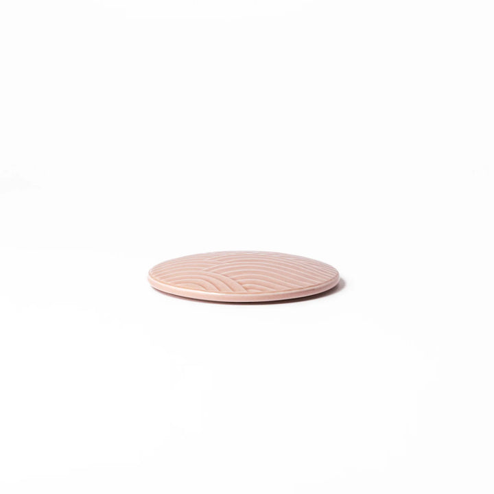 Soft pink porcelain lid with embossed Seigaiha wave design, crafted to pair with stackable Japanese bowls for elegant dining.
