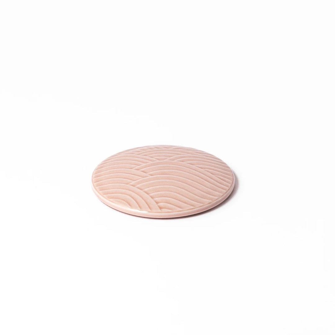 Soft pink porcelain lid with embossed Seigaiha wave design, crafted to pair with stackable Japanese bowls for elegant dining.