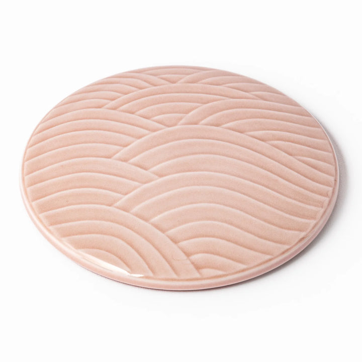 Soft pink porcelain lid with embossed Seigaiha wave design, crafted to pair with stackable Japanese bowls for elegant dining.
