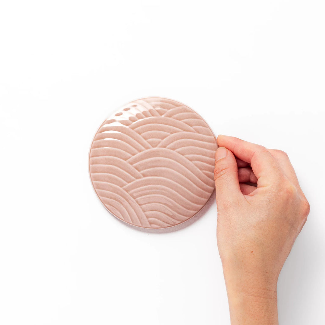 Soft pink porcelain lid with embossed Seigaiha wave design, crafted to pair with stackable Japanese bowls for elegant dining.