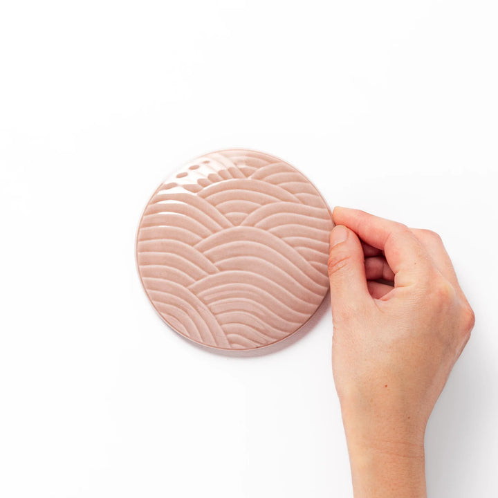 Soft pink porcelain lid with embossed Seigaiha wave design, crafted to pair with stackable Japanese bowls for elegant dining.