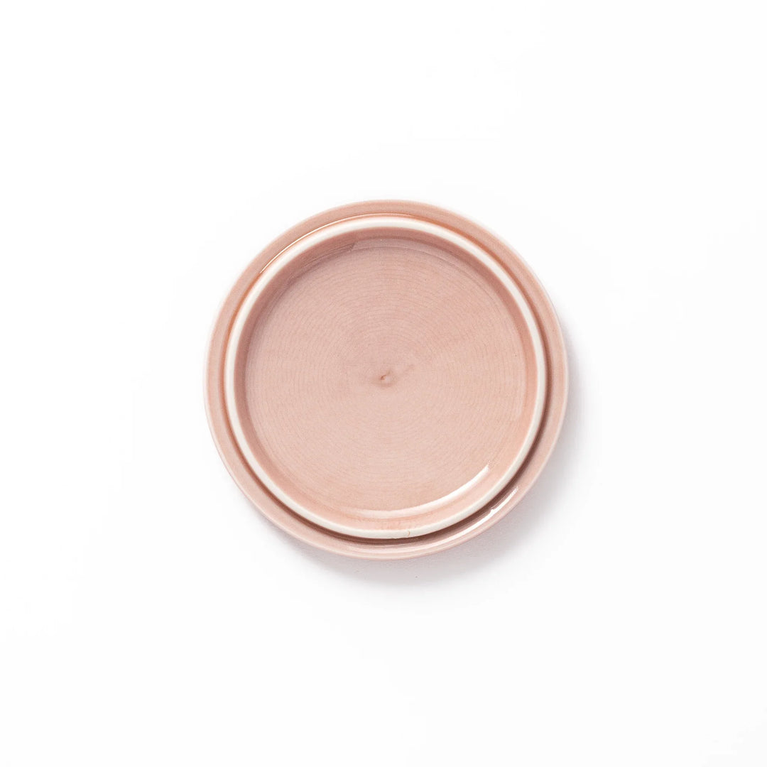 Soft pink porcelain lid with embossed Seigaiha wave design, crafted to pair with stackable Japanese bowls for elegant dining.