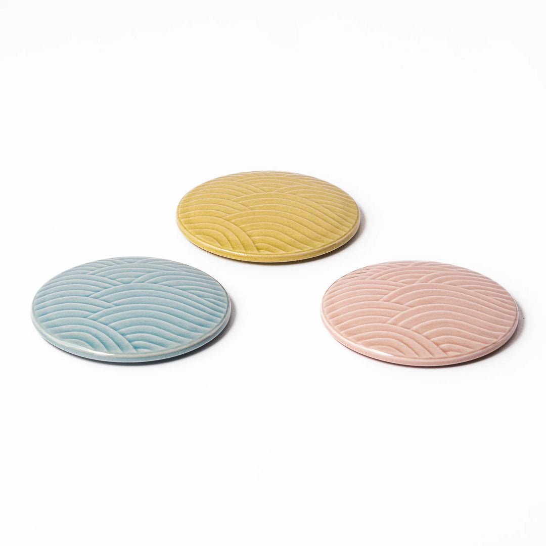 Three porcelain lids in pastel blue, yellow, and pink with embossed Seigaiha wave pattern for Japanese stackable bowls.