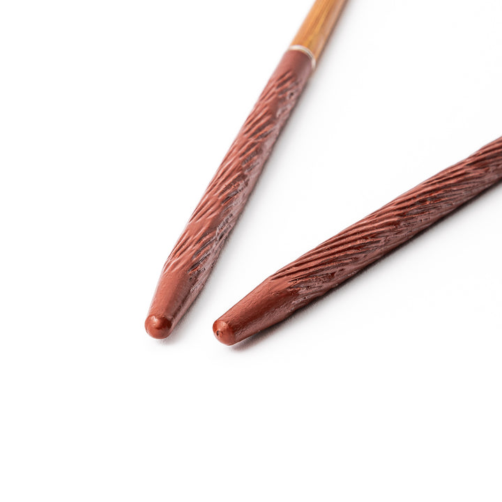 Portable Japanese travel chopsticks featuring a reddish brown textured handle with detailed carvings and a natural wood tip
