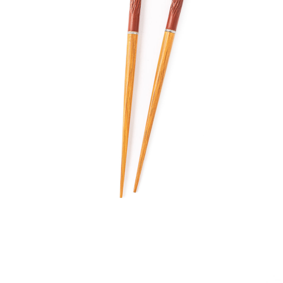 Portable Japanese travel chopsticks featuring a reddish brown textured handle with detailed carvings and a natural wood tip