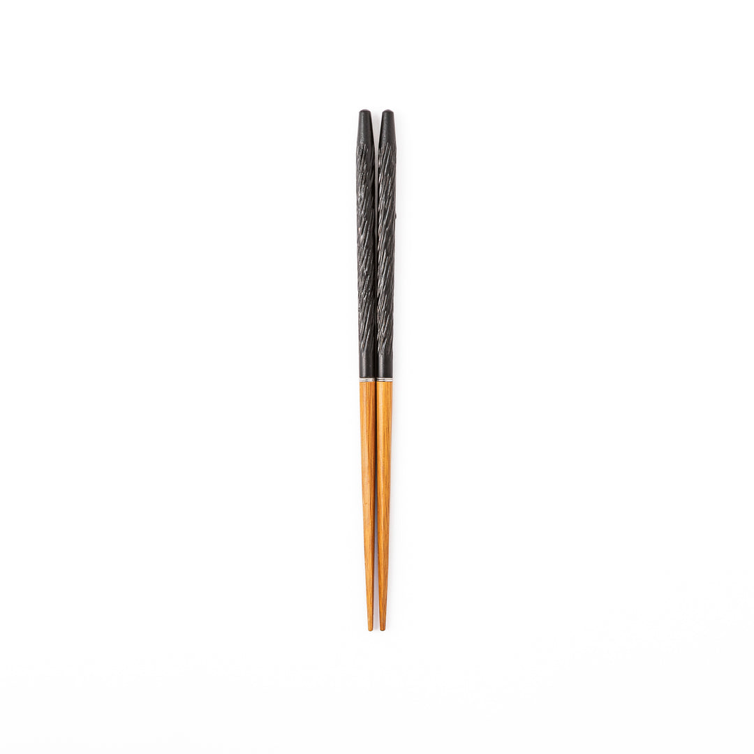Portable Japanese travel chopsticks featuring a black textured handle with detailed carvings and a natural wood tip