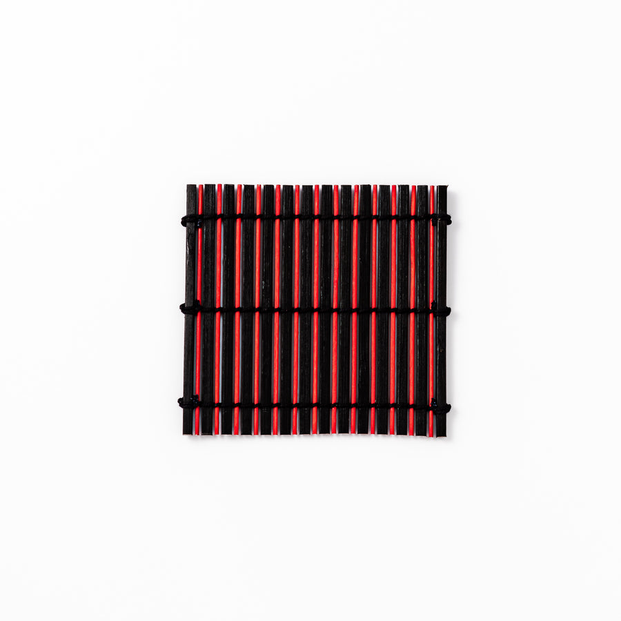 Red and black bamboo coaster with slim vertical slats and black cord ties, ideal for adding a striking accent to Japanese-style drink settings.