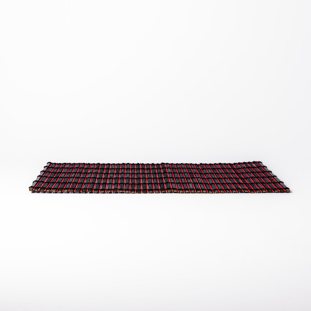 Red and black bamboo table mat with tightly spaced slats and black cord binding, adding bold color and texture to modern Japanese table settings.