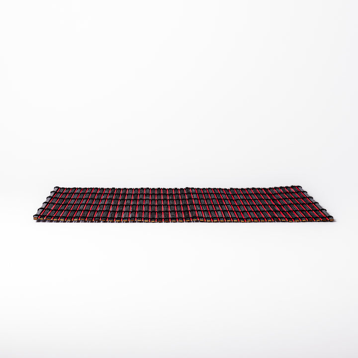 Red and black bamboo table mat with tightly spaced slats and black cord binding, adding bold color and texture to modern Japanese table settings.