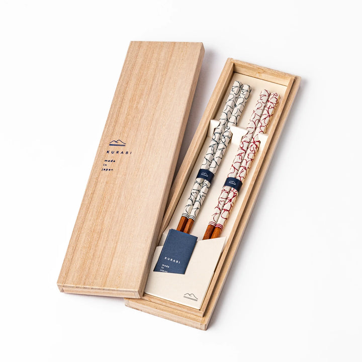 Red and blue Sakura Japanese chopsticks gift set with cherry blossom pattern handles in a wooden presentation box.