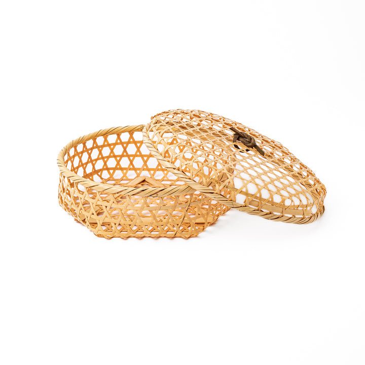 An open round handwoven bamboo serving basket with its hexagonal mesh pattern lid leaning slightly to the side