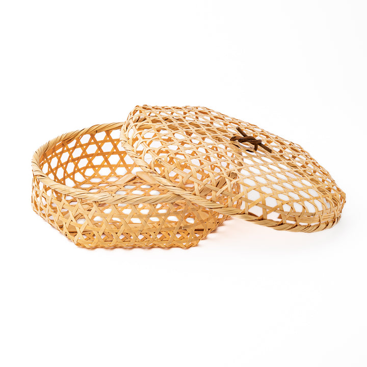 A medium round handwoven bamboo serving basket with a hexagonal mesh pattern lid resting on the woven border