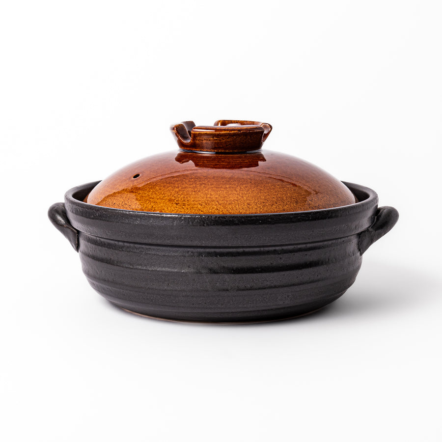 Japanese donabe clay pot with rustic brown glazed lid and black base, induction compatible and perfect for family hot pot meals.