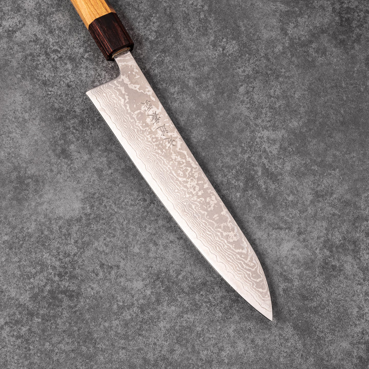 Japanese Damascus gyuto knife featuring a layered steel blade and natural wood handle displayed on gray stone background.
