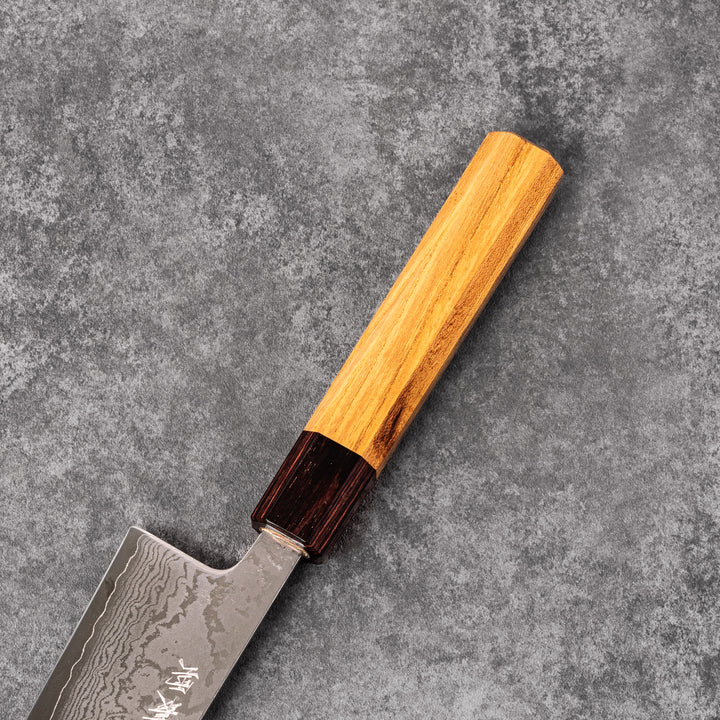 Japanese Damascus gyuto knife featuring a layered steel blade and natural wood handle displayed on gray stone background.