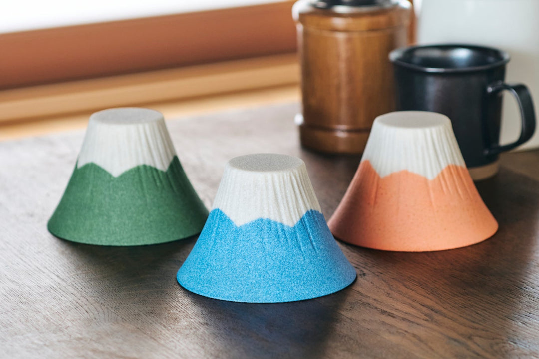 Colorful Mt Fuji shaped ceramic cups displayed on a wooden table in a cozy kitchen setting