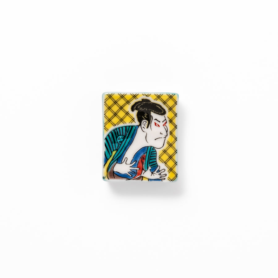 Rectangular Japanese ceramic chopstick rest featuring a bold kabuki actor design inspired by Sharaku’s ukiyo-e, adding dramatic artistry to dining tables.