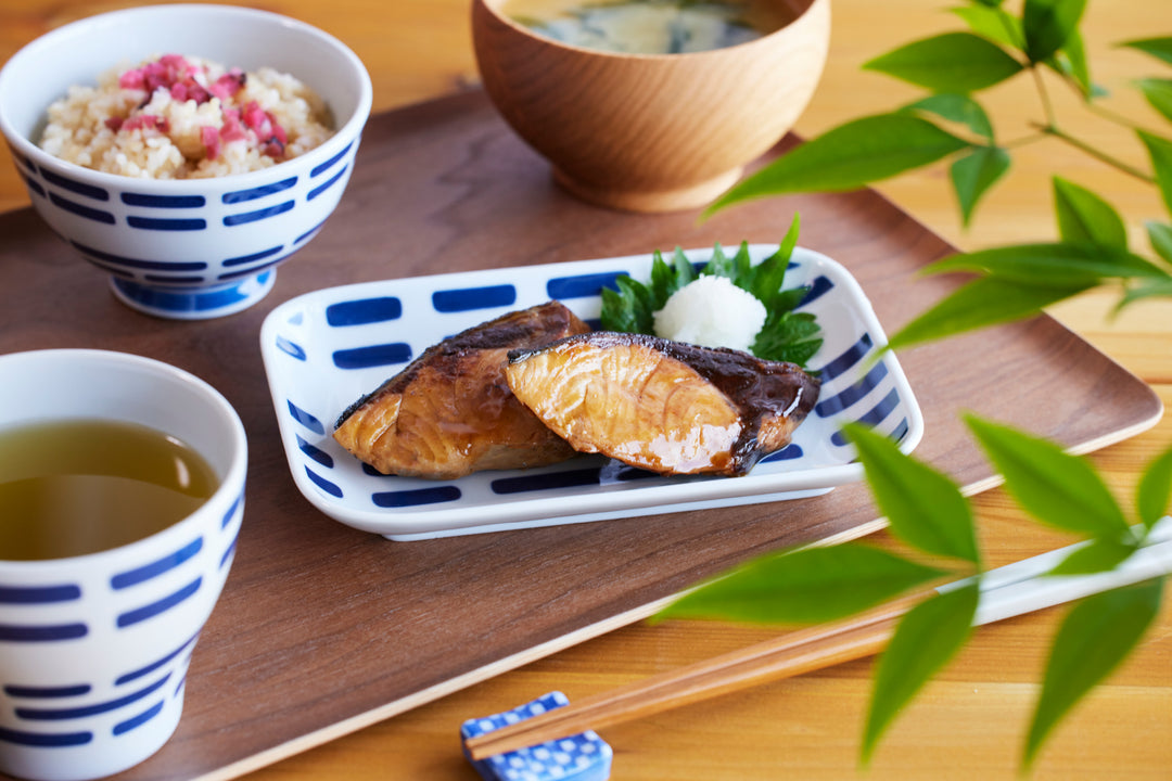 Japanese breakfast set with grilled fish served on a blue and white plate with rice tea and miso soup