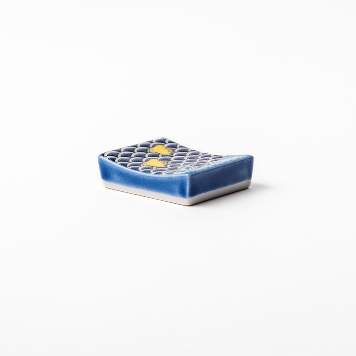 Rectangular Japanese ceramic chopstick rest decorated with a blue wave pattern and playful yellow shorebirds, adding charm and tradition to dining tables.