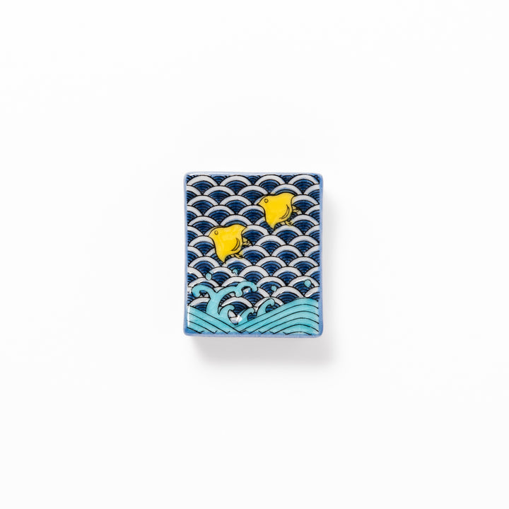 Rectangular Japanese ceramic chopstick rest decorated with a blue wave pattern and playful yellow shorebirds, adding charm and tradition to dining tables.