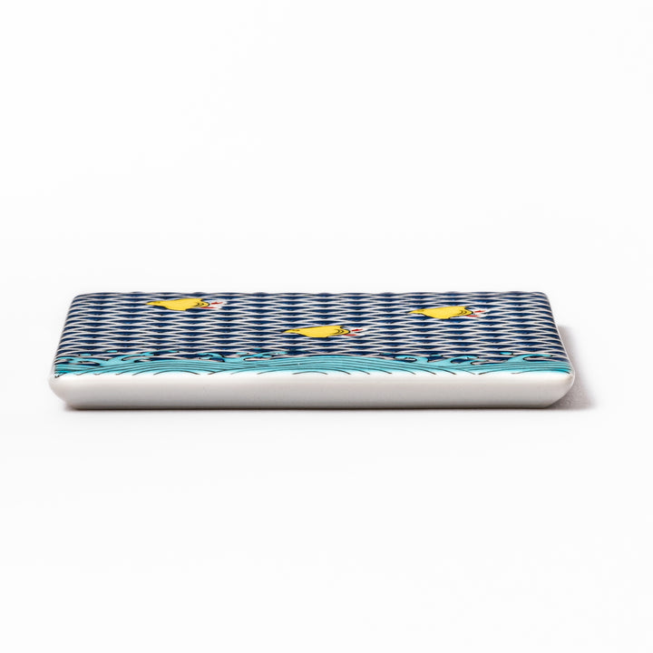 Square Japanese ceramic coaster with traditional blue wave pattern and yellow shorebirds, combining artistry and function for stylish dining table settings.
