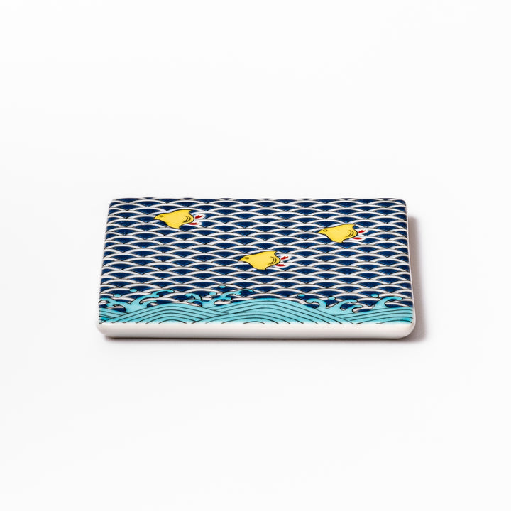 Square Japanese ceramic coaster with traditional blue wave pattern and yellow shorebirds, combining artistry and function for stylish dining table settings.