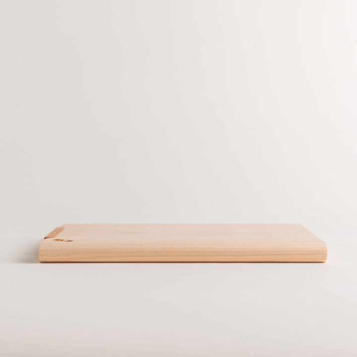 Small Hinoki wood cutting board with smooth grain, natural finish, corner handle, and engraved motif, crafted in Japan
