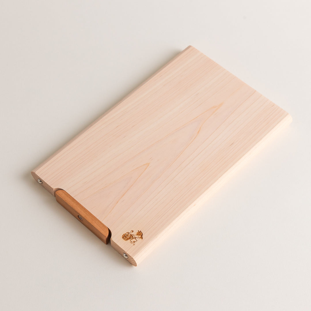 Small Hinoki wood cutting board with smooth grain, natural finish, corner handle, and engraved motif, crafted in Japan