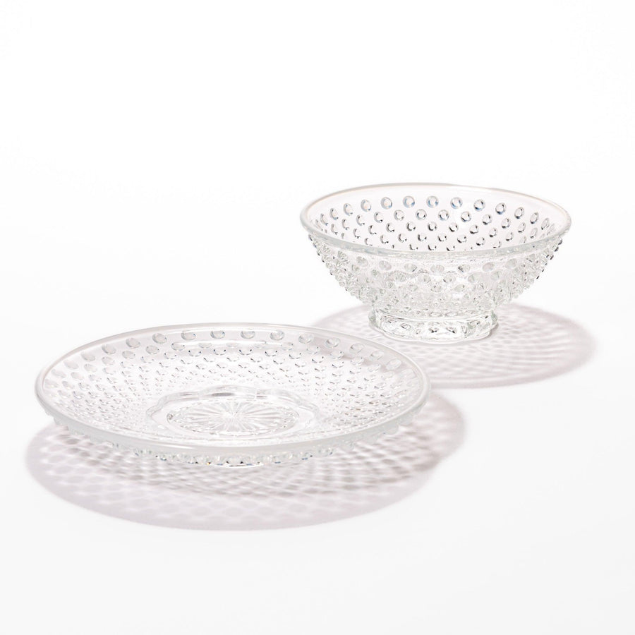 Clear glass dessert bowl and saucer set featuring raised dot texture and starburst base, ideal for elegant desserts or refreshing fruit.