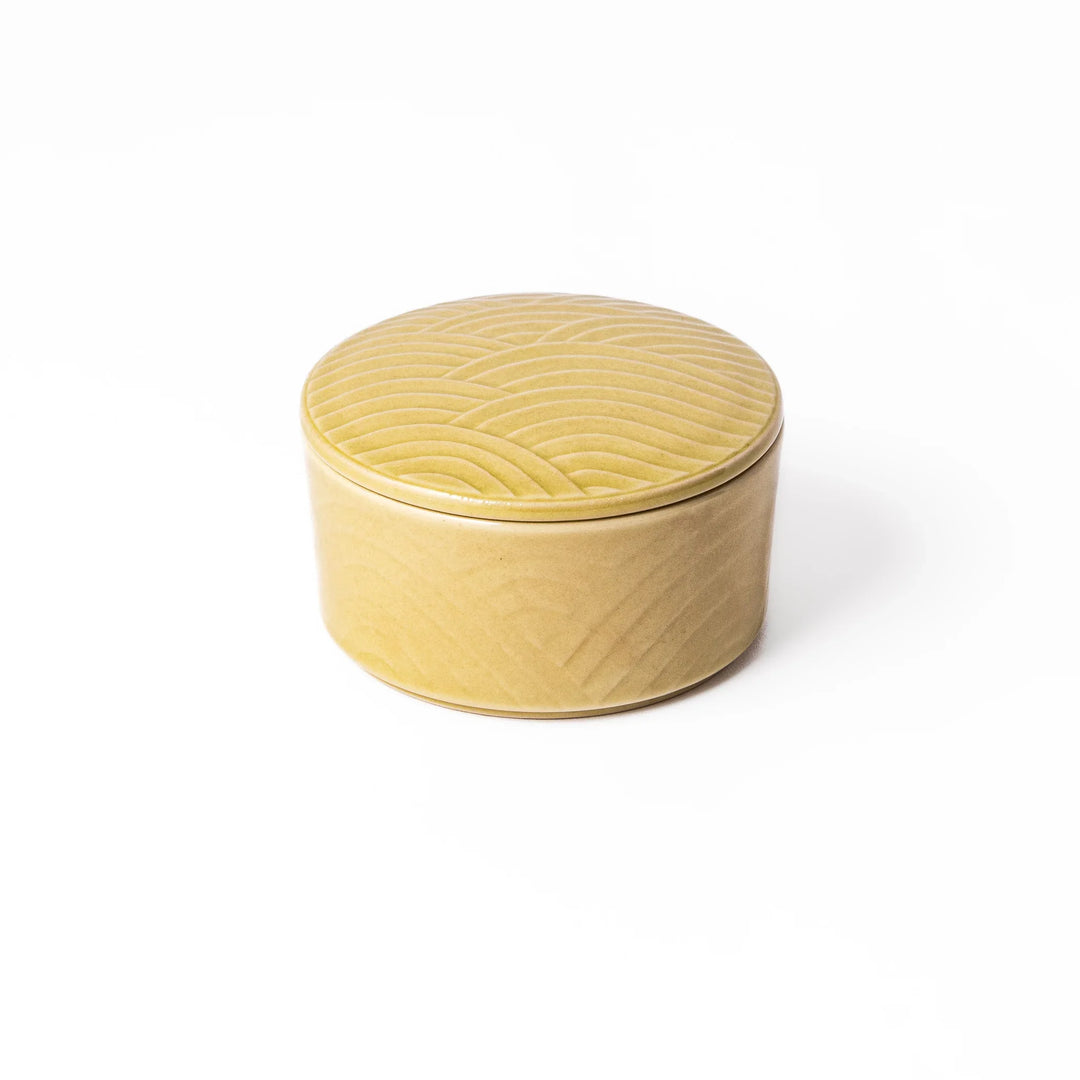 Yellow stackable porcelain bowl with matching embossed lid featuring a Japanese Seigaiha wave pattern in a smooth matte glaze.