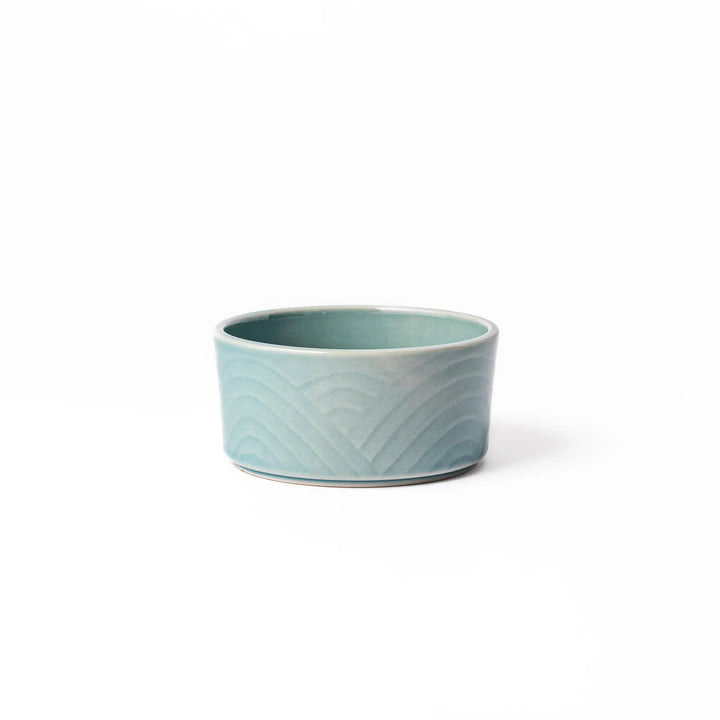 Light blue stackable porcelain bowl with embossed Seigaiha wave pattern, showcasing smooth matte texture and minimalist Japanese design.