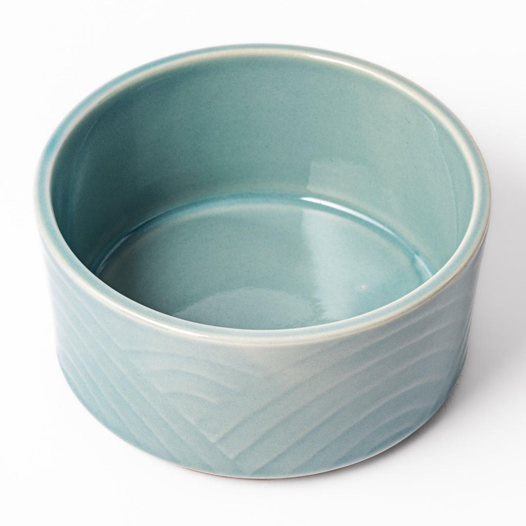 Light blue stackable porcelain bowl with embossed Seigaiha wave pattern, showcasing smooth matte texture and minimalist Japanese design.