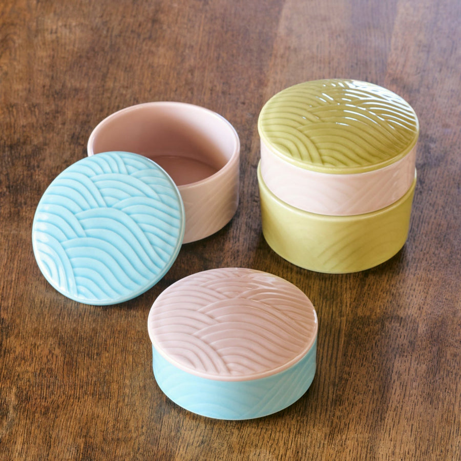 Stackable Japanese porcelain boxes in yellow, blue, and pink with wave pattern lids, perfect for storing condiments or small treats with an elegant modern touch.