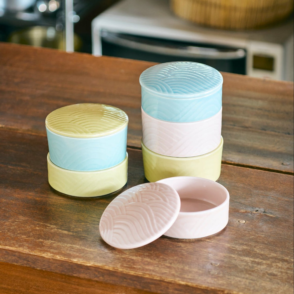 Stackable Japanese porcelain boxes in yellow, blue, and pink with wave pattern lids, perfect for storing condiments or small treats with an elegant modern touch.
