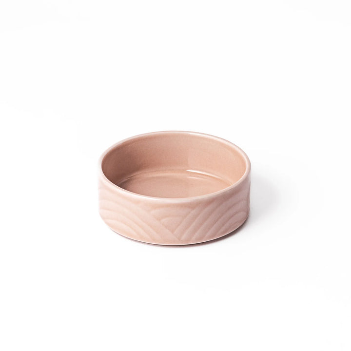 Light pink porcelain bowl with embossed Japanese wave pattern, simple cylindrical shape and glossy finish on a white background.