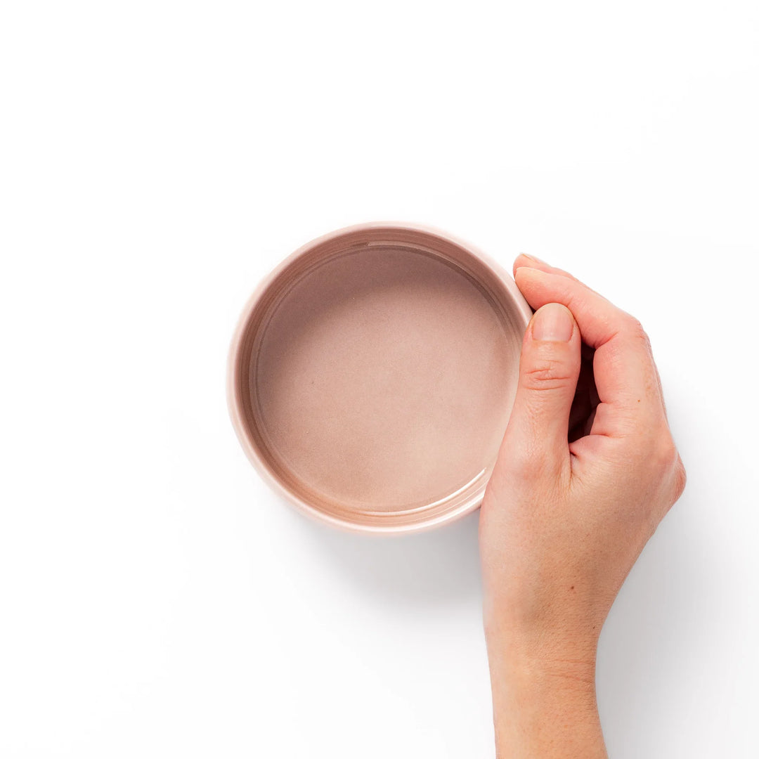 Light pink porcelain bowl with embossed Japanese wave pattern, simple cylindrical shape and glossy finish on a white background.