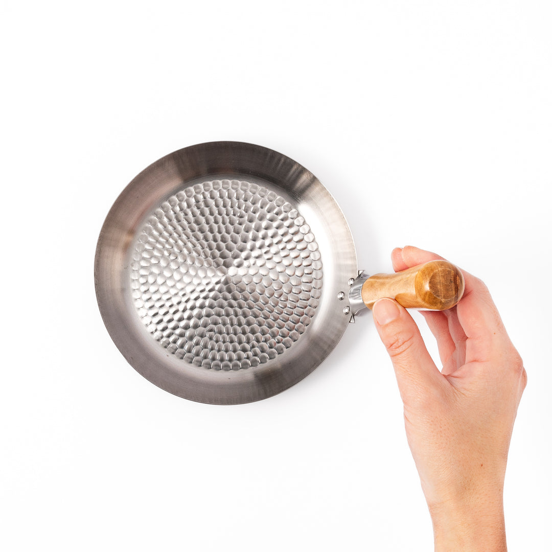 Japanese stainless steel donburi pot with a wooden handle and hammered base, designed for evenly heating and serving rice bowls, simmered dishes, and sauces.