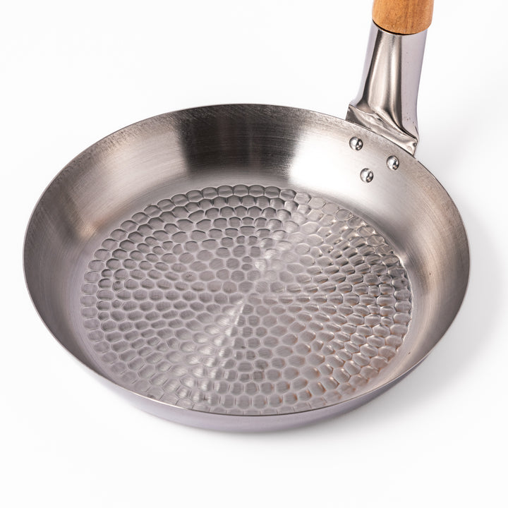 Japanese stainless steel donburi pot with a wooden handle and hammered base, designed for evenly heating and serving rice bowls, simmered dishes, and sauces.