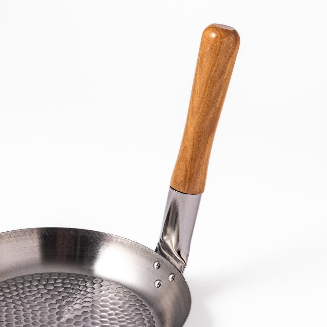 Japanese stainless steel donburi pot with a wooden handle and hammered base, designed for evenly heating and serving rice bowls, simmered dishes, and sauces.