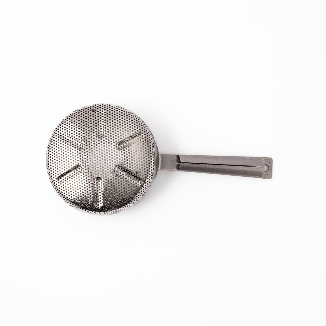 Japanese stainless steel hand coffee roaster with perforated drum and long handle, designed for evenly roasting coffee beans over open flame at home.