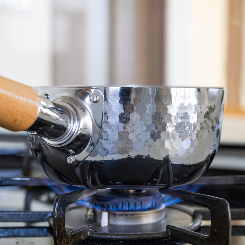 Stainless Steel Yukihira Pot heating over gas flame with hammered finish and wooden handle