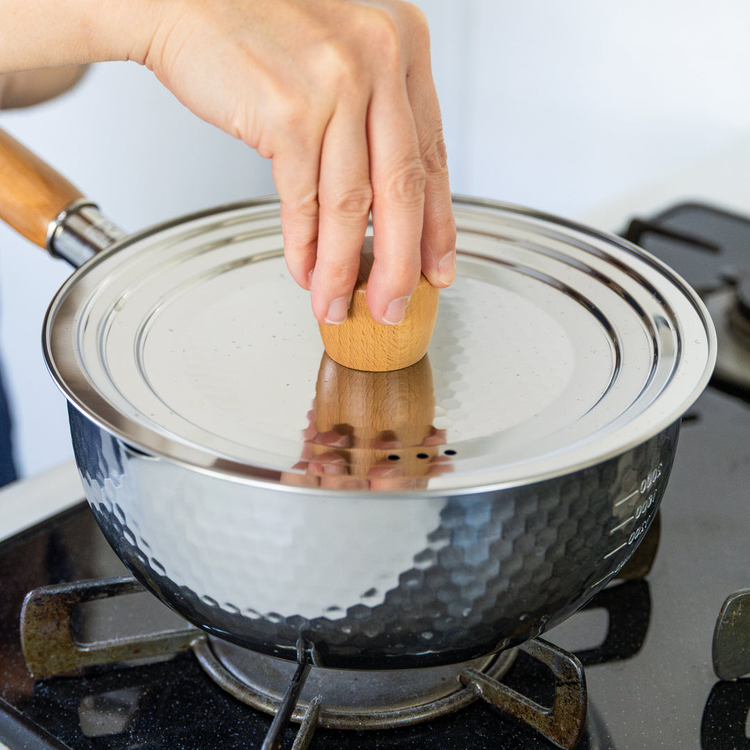 Stainless Steel Yukihira Pot with lid and wooden knob simmering on gas stove