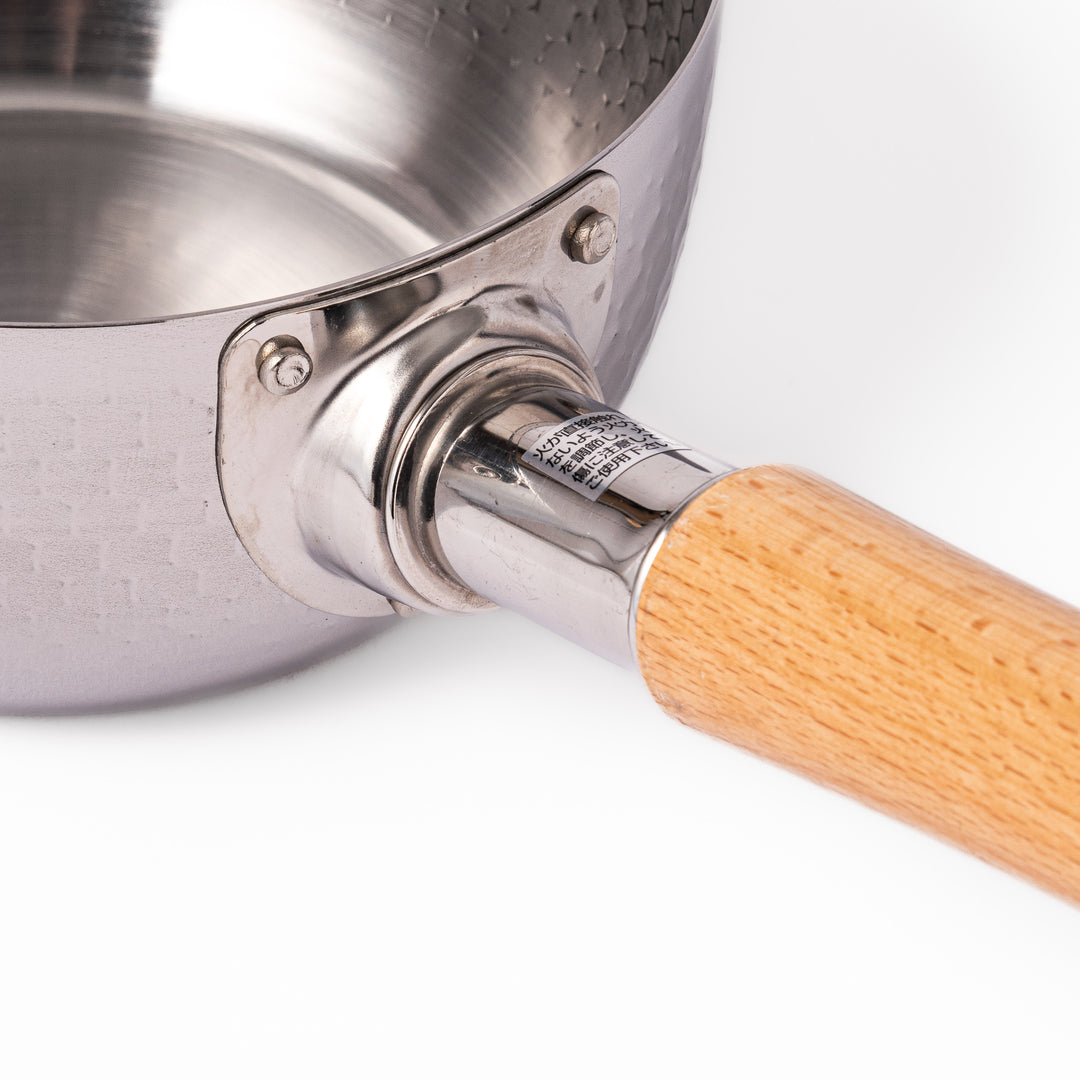 Japanese stainless steel Yukihira pot with a wooden handle and hammered finish, featuring twin pour spouts for easy cooking, simmering, and sauce preparation.