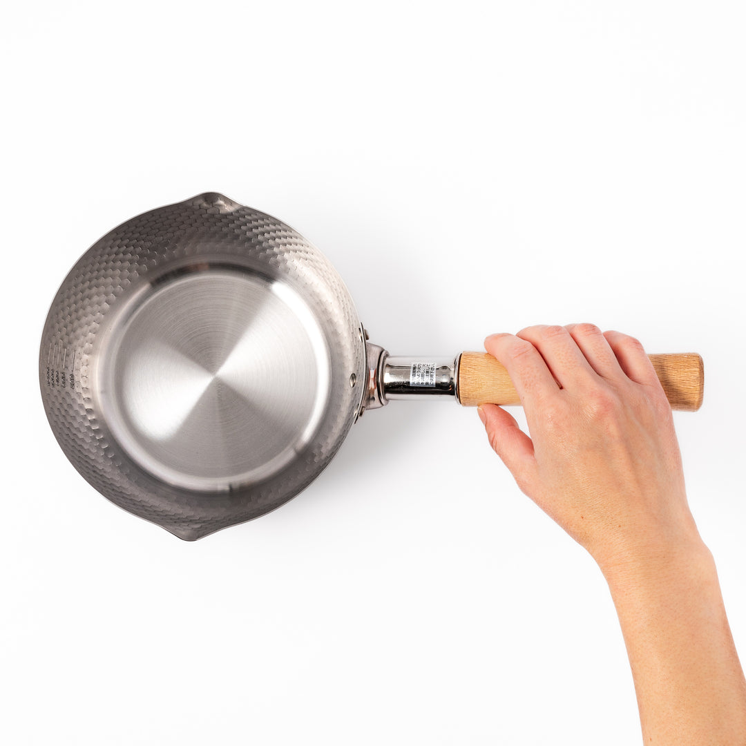 Stainless steel Yukihira pot with a wooden handle featuring a hammered texture and dual pour spouts, ideal for making soups, sauces, and everyday Japanese cooking.