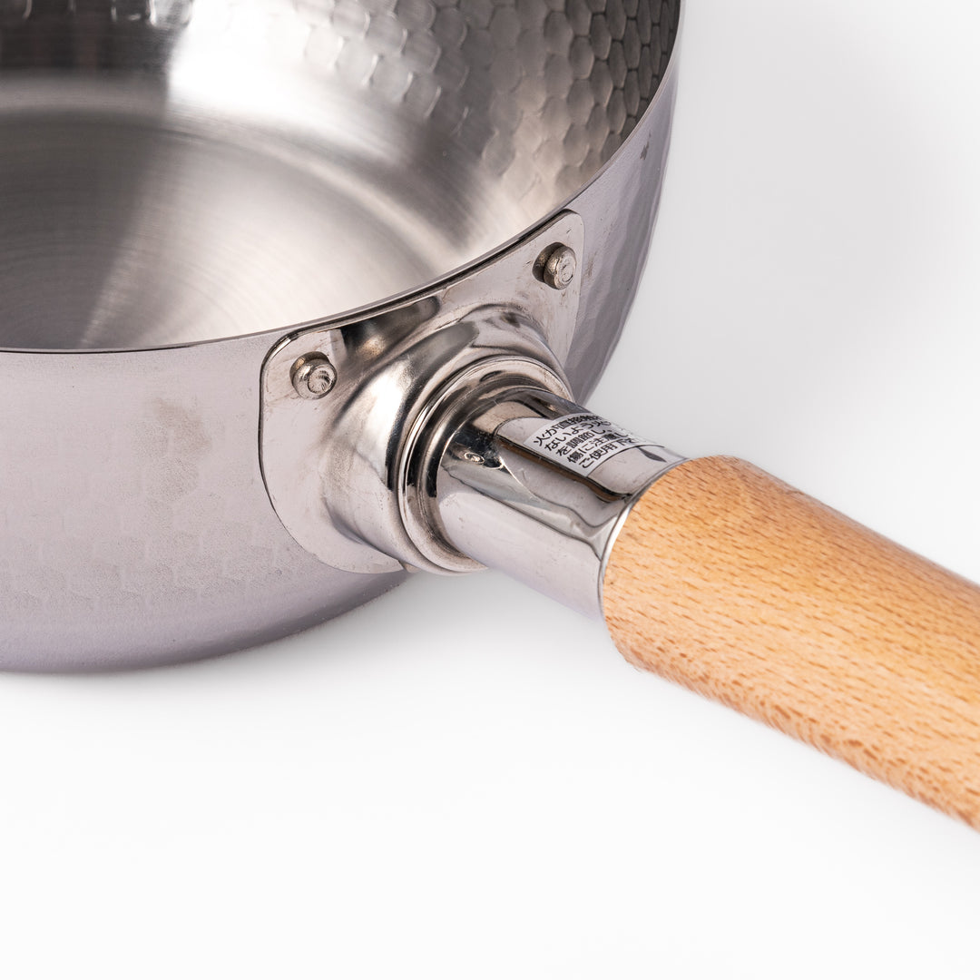 Stainless steel Yukihira pot with a wooden handle featuring a hammered texture and dual pour spouts, ideal for making soups, sauces, and everyday Japanese cooking.