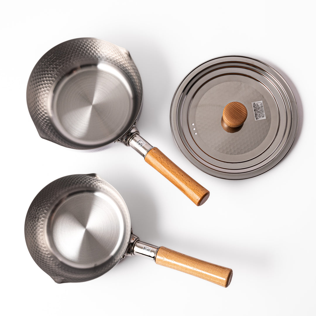 Set of Japanese stainless steel Yukihira pots with wooden handles and matching lid, featuring hammered texture and dual spouts for versatile everyday cooking.
