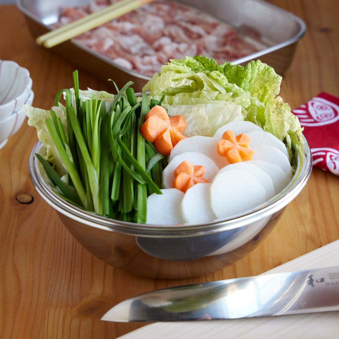 Stainless steel mixing bowl filled with napa cabbage, daikon, carrots, and garlic chives prepared for Japanese hot pot cooking.