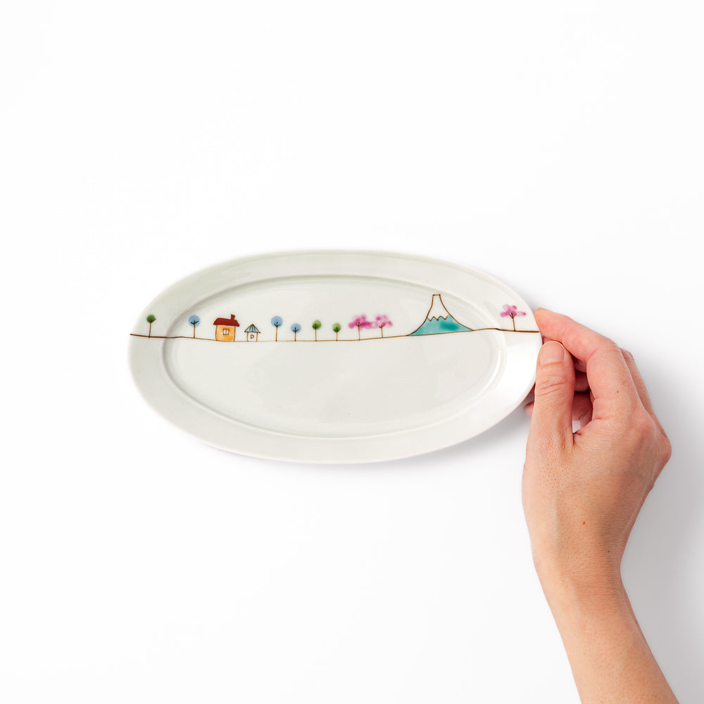 Japanese porcelain oval plate with whimsical Japan design featuring Mount Fuji, cherry blossoms, houses, and colorful trees
