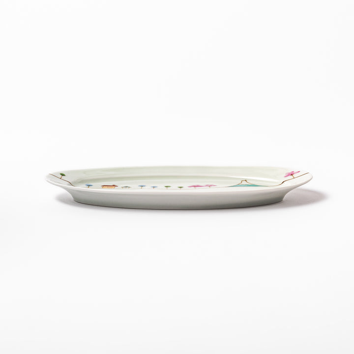 Japanese porcelain oval plate with whimsical Japan design featuring Mount Fuji, cherry blossoms, houses, and colorful trees